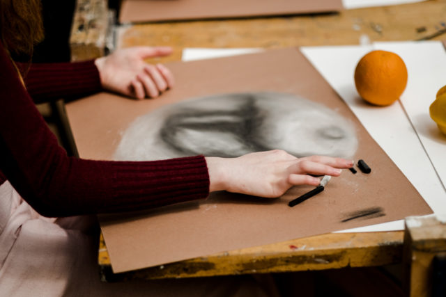 A student creating a piece of art at a desk in the art department.