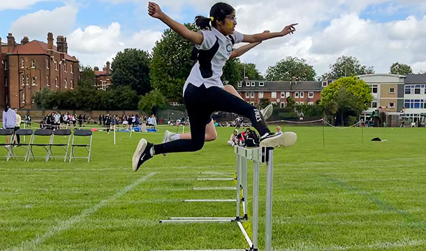 A student running the hurdles race on the field as part of Sports Day.
