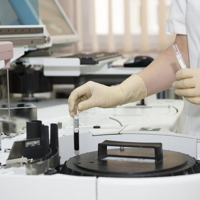 Chemist with glove picking up test tube